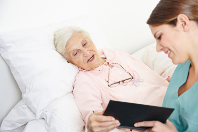 woman showing something to elderly woman in bed